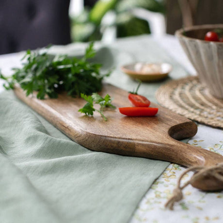 Wooden cutting board with herbs and tomatoes on a tablecloth