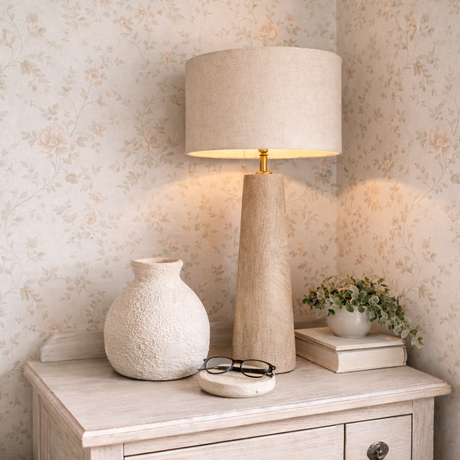 Decorative lamp and vase on a wooden cabinet with floral wallpaper.