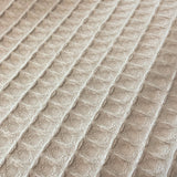 Close-up of textured beige fabric with a diamond pattern
