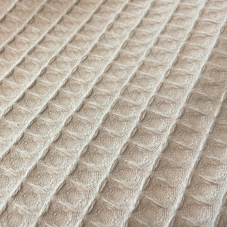 Close-up of textured beige fabric with a diamond pattern