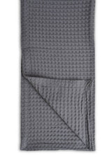 Grey textured blanket folded on a white background