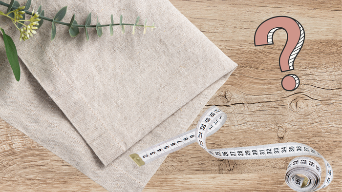 Linen fabric with a measuring tape and question mark on a wooden surface