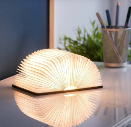 Wooden book-shaped lamp on a desk with a blurred background