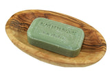 Green bar of soap on a wooden soap dish with 'Oliven Provence' branding.