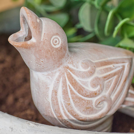 terracotta bird watering spike sculpture with intricate designs on a natural background