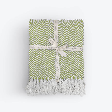 Green and white patterned blanket with tassels on a white background