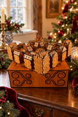 Cherry wood Christmas Advent Village displayed on its decorative storage box beside a Christmas tree and festive greenery.