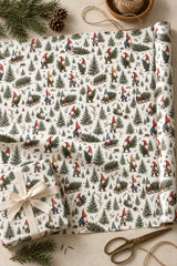 Tree Harvest gnome wrapping paper unrolled beside a cream-ribbon parcel and brass scissors.