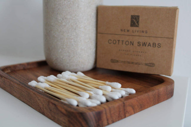 Cotton swabs on a wooden tray with a New Living box in the background