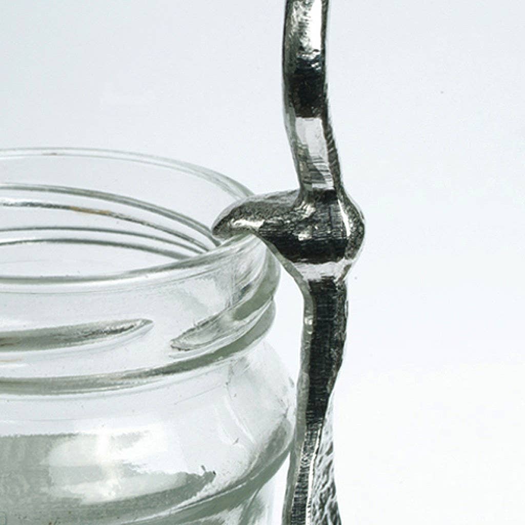 Glass jar with a metal spoon inside on a white background