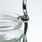 Glass jar with a metal spoon inside on a white background