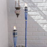 Two blue torches with flames against a white brick wall.