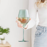 Person holding a textured wine glass with a light-colored background