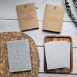  natural pop-up dish sponges on a wooden tray with packaging and eucalyptus leaves on a wooden surface.