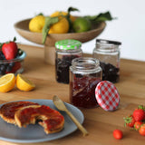 Jars of jam on a wooden table with fruit and bread