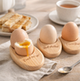 Set of wooden egg holders with engraved text on a wooden surface.
