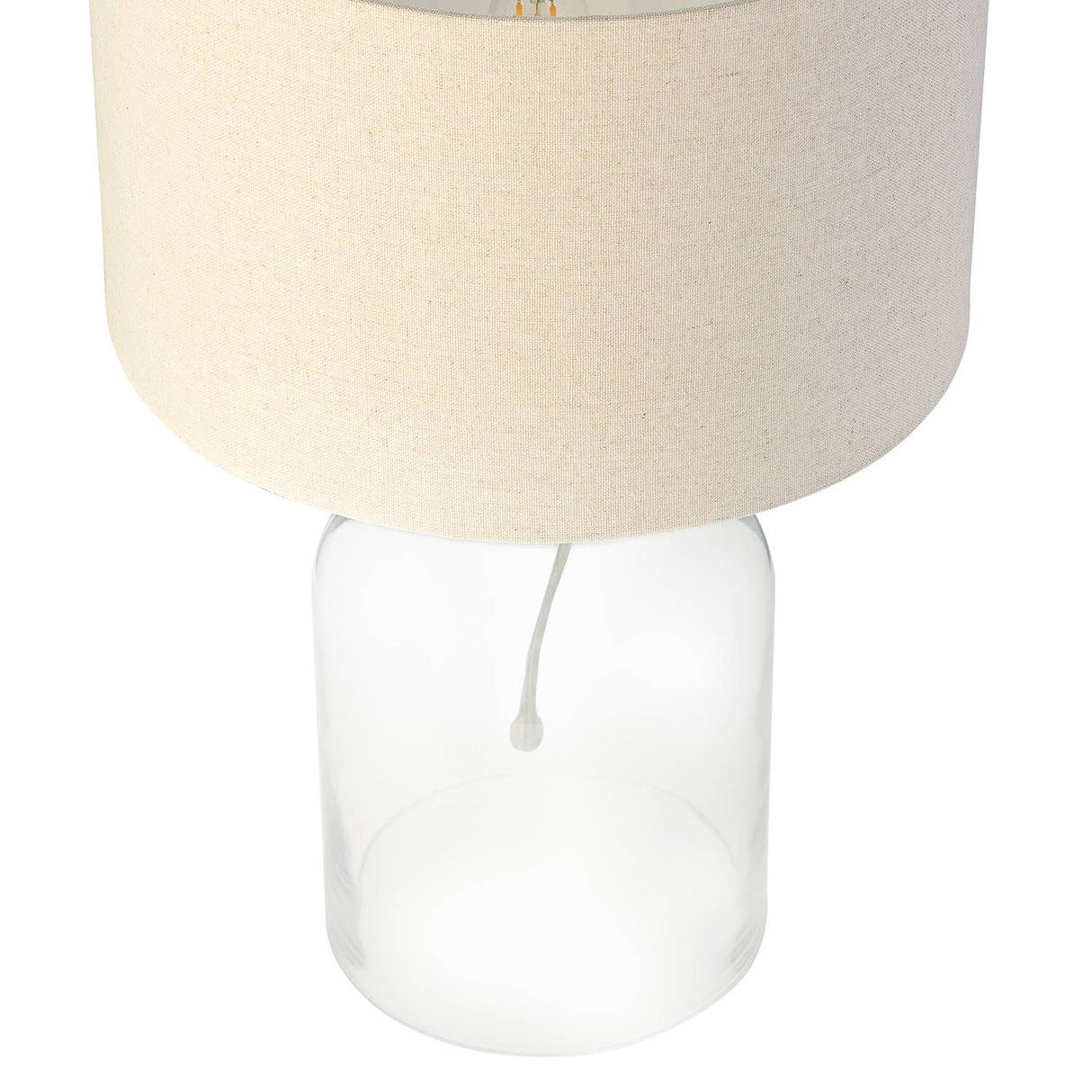 Lamp with beige fabric shade and clear glass base on a white background
