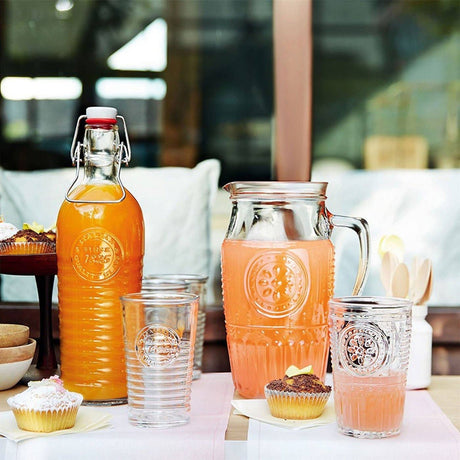 Table setting with bottles, glasses, and cupcakes on a blurred outdoor background