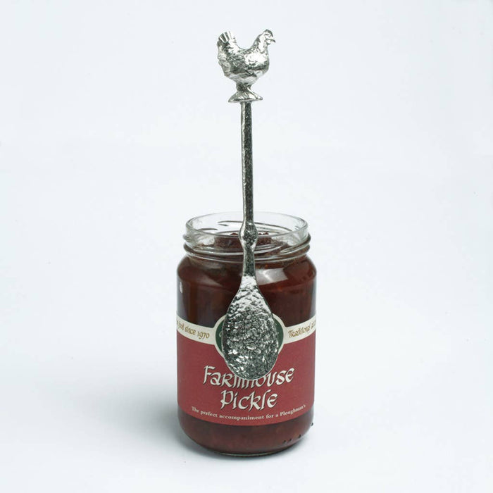 Jar of farmhouse pickle with a decorative spoon with a chicken on top on a white background