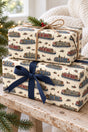 Two canal boat Christmas parcels tied with navy ribbon and natural twine on a pale wooden bench.