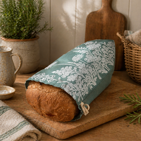Loaf of bread wrapped in a floral-patterned green cloth on a wooden surface with a rustic background.
