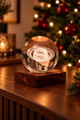 Saturn crystal lamp on a walnut console with the ringed planet glowing, framed by fir sprigs and a Christmas tree with red baubles.