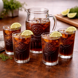 Pitcher and glasses of iced tea with lemon slices on a wooden table.