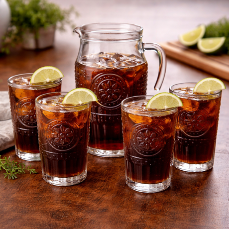 Pitcher and glasses of iced tea with lemon slices on a wooden table.