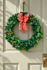 Green recycled sari fabric wreath with bow on a door