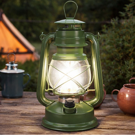 Green camping lantern with battery compartment and light on a white background