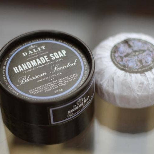 Handmade soap in a black container with a white soap bar on a reflective surface