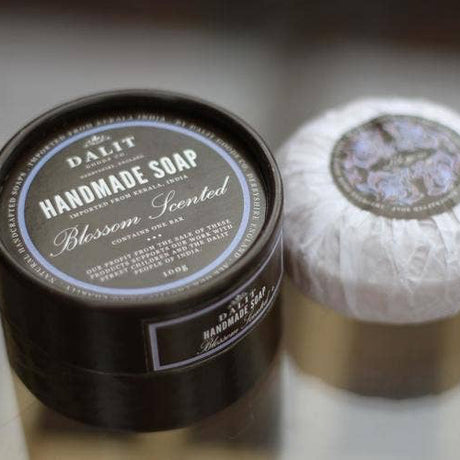 Handmade soap in a black container with a white soap bar on a reflective surface