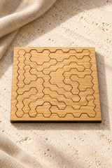 Assembled Hard Hex wooden tessellation puzzle on pale limestone, showing its square board and geometric piece pattern.