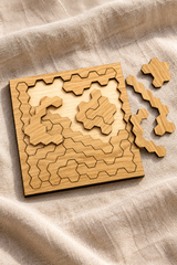 Close-up of the partly assembled square Hard Hex puzzle on linen, showing pale oak grain and intricate angular pieces.