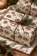 Close-up of a gift wrapped in hedgehog and holly Christmas paper with burgundy ribbon.