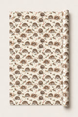 Hedgehog Christmas wrapping paper roll with brown hedgehogs, holly and pine cones on a cream background.