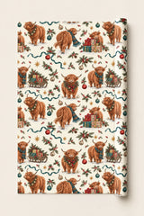 Large-pattern Highland cow Christmas wrapping paper roll with festive cows, presents and holly on a cream background