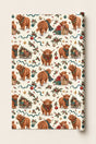 Large-pattern Highland cow Christmas wrapping paper roll with festive cows, presents and holly on a cream background