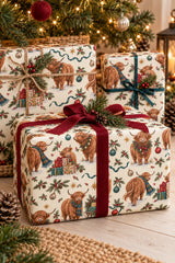 Large-pattern Highland cow Christmas wrapping paper around gifts beneath a decorated Christmas tree