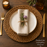 Dining table setting with woven placemat, ceramic plate, gold cutlery, and candle.