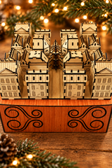 Close-up of the light wood Advent Village houses, showing engraved details and dark laser-cut edges in a Christmas setting.