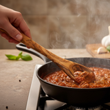 Wooden spoon on a towel with ingredients in the background