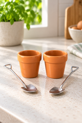 Pair of empty plant pot egg cups with two steel shovel spoons