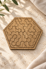 Assembled Pocket Hex wooden tessellation puzzle on pale limestone with a linen edge and soft leaf shadows.