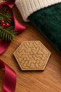 Small Pocket Hex wooden puzzle beside a forest-green Christmas stocking, burgundy ribbon and fir sprigs.