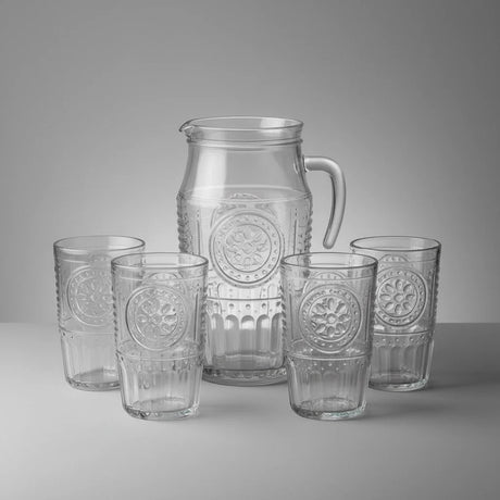 Set of clear glass pitcher and tumblers with embossed designs on a gray background
