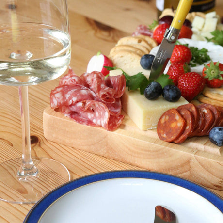 30 × 20cm rubberwood charcuterie board with cured meats, cheese, berries and crackers beside a glass of white wine.