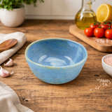 Blue  bowl on a wooden table with kitchen items in the background