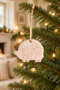 Whitewashed terracotta hedgehog Christmas decoration on a fir branch