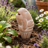 Decorative terracotta watering spike in a garden with flowers and plants